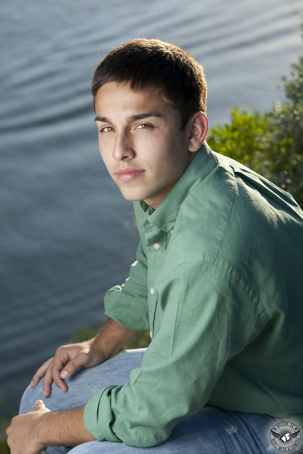 High school graduation photography in Austin of boy in green shirt on Lake Austin at the 360 Bridge overlook.